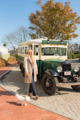 Woman standing in front of an old vintage Ford bus with her small dog at the Nantucket Hotel